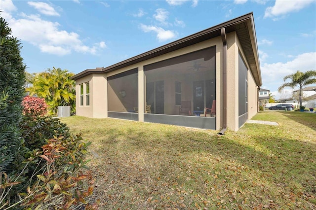 rear view of house with central air condition unit, a sunroom, and a yard