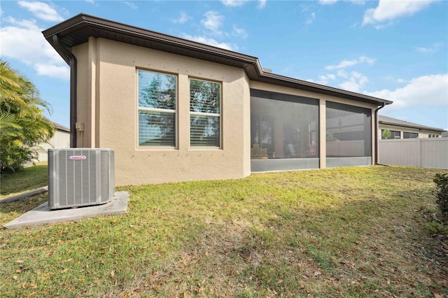 rear view of house with a sunroom, central air condition unit, and a yard