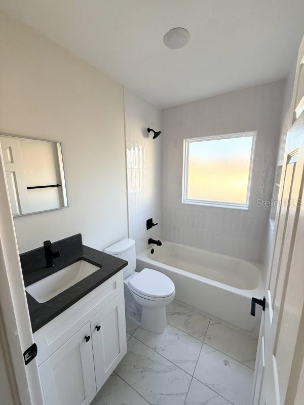 full bathroom with vanity, tiled shower / bath combo, and toilet