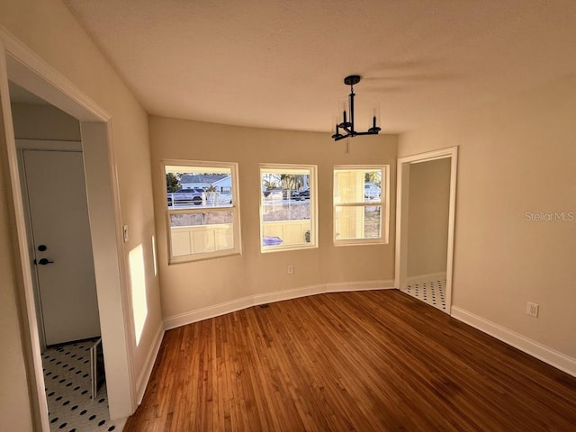 spare room featuring hardwood / wood-style floors and a chandelier