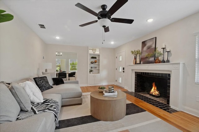 living room with ceiling fan, a fireplace, and light hardwood / wood-style floors