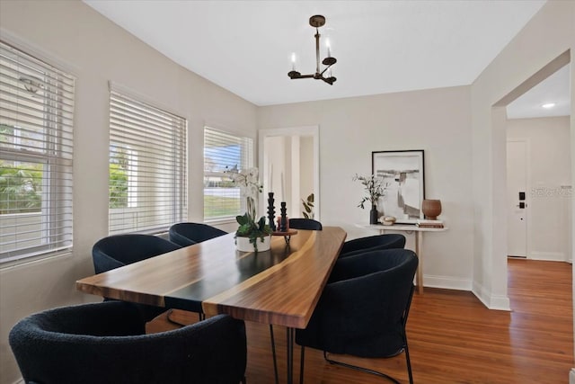 dining area with wood-type flooring and an inviting chandelier