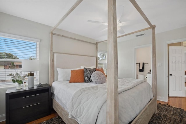 bedroom with ceiling fan, ensuite bath, hardwood / wood-style floors, and multiple windows