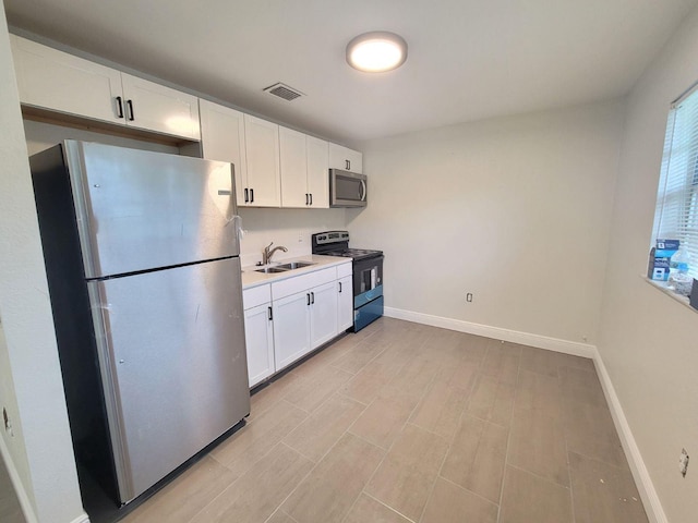 kitchen with white cabinetry, sink, light wood-type flooring, and appliances with stainless steel finishes