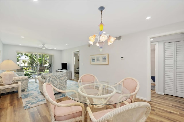 dining room with ceiling fan with notable chandelier and light hardwood / wood-style flooring