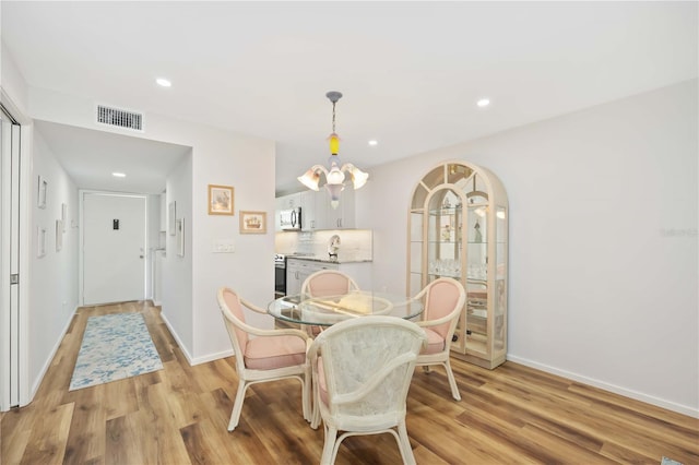 dining area with light hardwood / wood-style floors and a chandelier