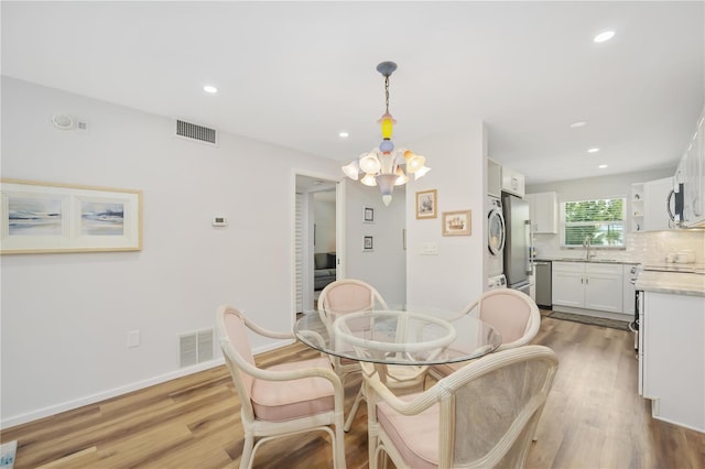 dining area with light wood-type flooring and a notable chandelier