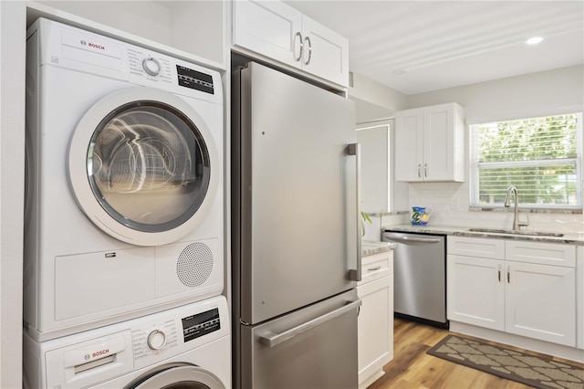 laundry room featuring sink, light wood-type flooring, and stacked washer and dryer