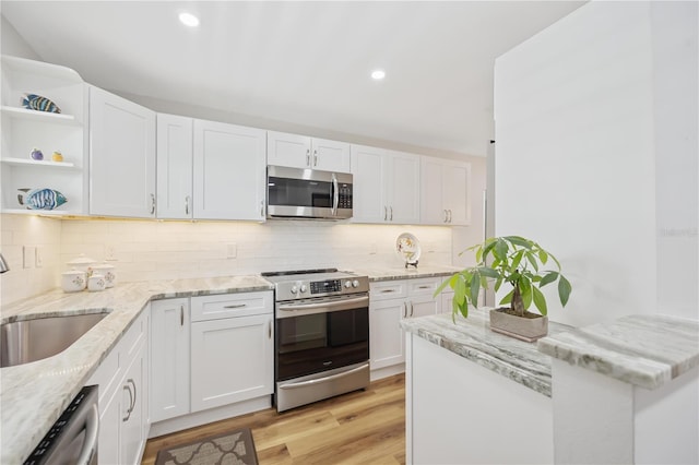 kitchen featuring light stone countertops, appliances with stainless steel finishes, sink, light hardwood / wood-style flooring, and white cabinets