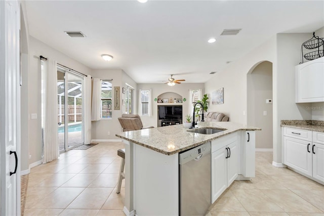 kitchen with ceiling fan, sink, stainless steel dishwasher, a kitchen island with sink, and white cabinets