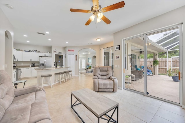 tiled living room with ceiling fan and sink