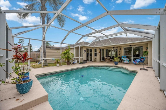 view of pool featuring a patio, glass enclosure, and ceiling fan