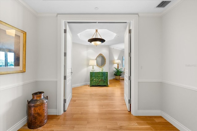 hallway featuring light hardwood / wood-style floors, a raised ceiling, and crown molding