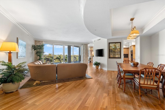 dining area with a tray ceiling, light hardwood / wood-style flooring, and ornamental molding