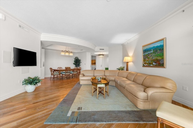 living room with hardwood / wood-style flooring, a notable chandelier, and ornamental molding