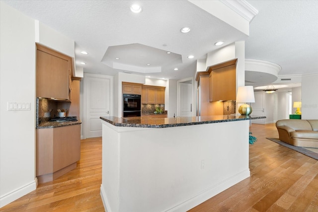 kitchen with decorative backsplash, dark stone countertops, kitchen peninsula, and light hardwood / wood-style flooring