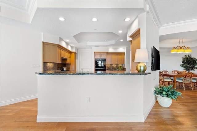 kitchen with backsplash, crown molding, light wood-type flooring, decorative light fixtures, and kitchen peninsula