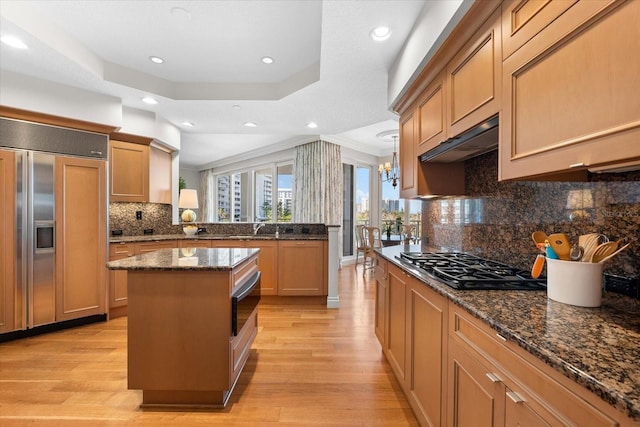 kitchen with a center island, crown molding, dark stone countertops, tasteful backsplash, and paneled fridge