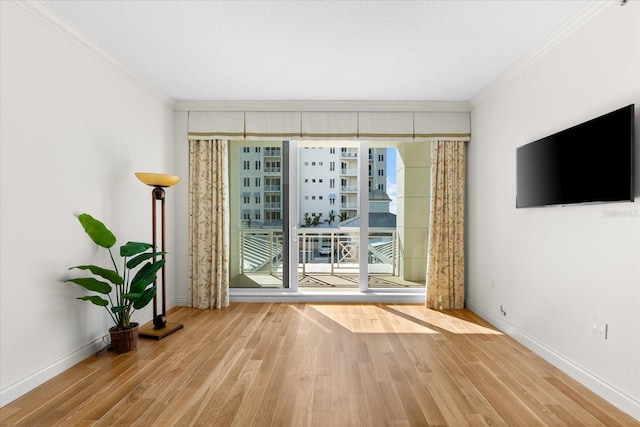 empty room with floor to ceiling windows, crown molding, and light wood-type flooring