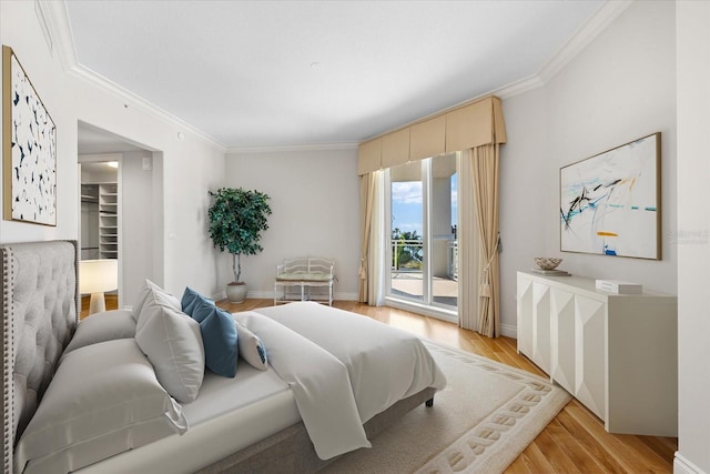 bedroom featuring access to exterior, a walk in closet, light hardwood / wood-style floors, and crown molding