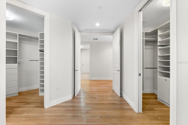 corridor featuring a textured ceiling and light hardwood / wood-style flooring