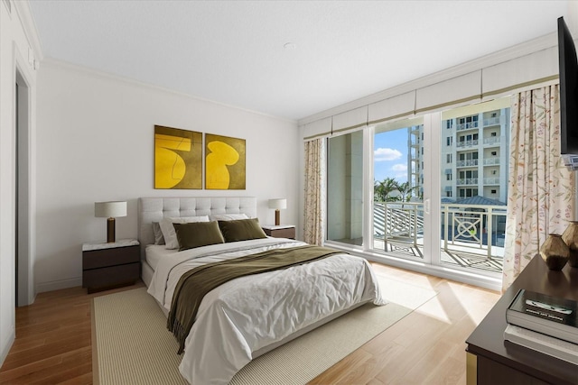 bedroom featuring hardwood / wood-style floors, access to exterior, and ornamental molding