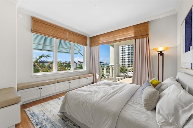 bedroom featuring light wood-type flooring, ornamental molding, and access to outside