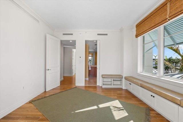 interior space with light wood-type flooring and crown molding