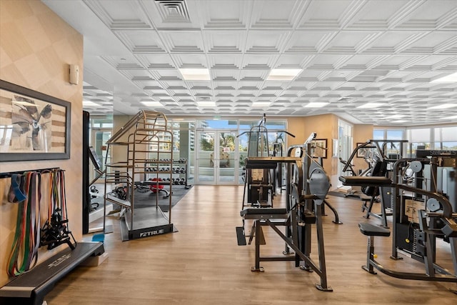 exercise room with french doors and light wood-type flooring