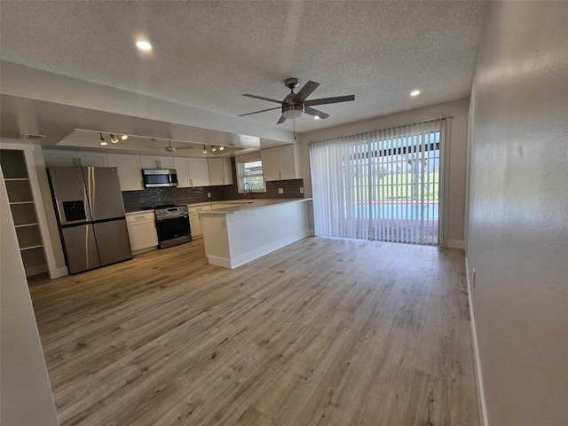 kitchen featuring light hardwood / wood-style flooring, white cabinets, a healthy amount of sunlight, and appliances with stainless steel finishes