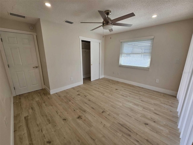 unfurnished bedroom with a closet, ceiling fan, light hardwood / wood-style flooring, and a textured ceiling