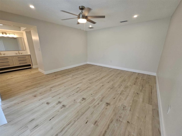 unfurnished room featuring ceiling fan, sink, a textured ceiling, and light hardwood / wood-style flooring