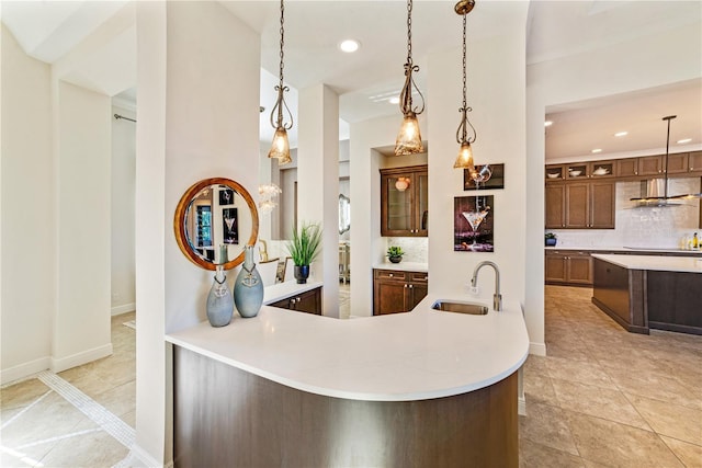 interior space featuring kitchen peninsula, extractor fan, pendant lighting, backsplash, and sink