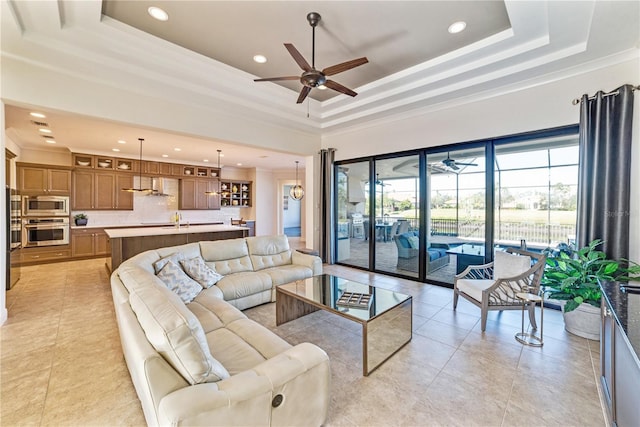 living area with light tile patterned floors, a tray ceiling, a ceiling fan, and ornamental molding