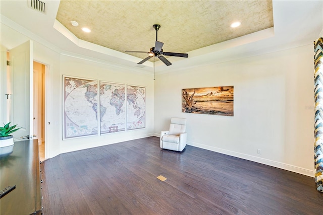 unfurnished room featuring a tray ceiling, dark wood-style flooring, visible vents, and baseboards