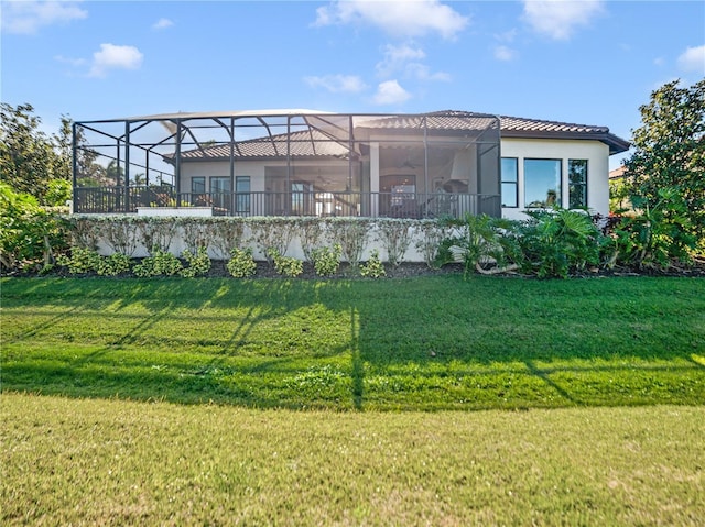 rear view of property with a lawn, a lanai, and stucco siding