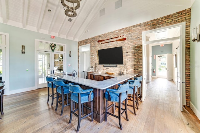 kitchen with light wood finished floors, beamed ceiling, a wealth of natural light, and a kitchen breakfast bar