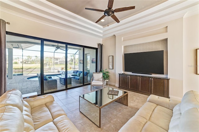 living room featuring light tile patterned floors, baseboards, a ceiling fan, a sunroom, and a tray ceiling