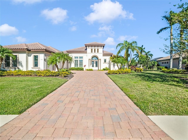 mediterranean / spanish house featuring french doors, decorative driveway, a front yard, and a tile roof