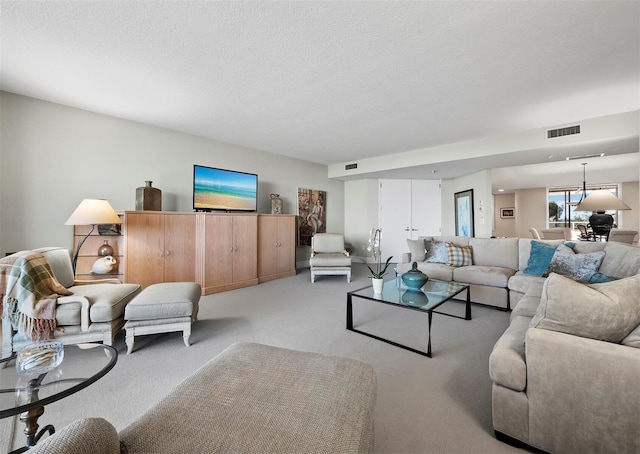 carpeted living area featuring visible vents and a textured ceiling