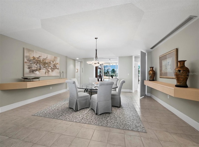 tiled dining room with a textured ceiling, a notable chandelier, and baseboards