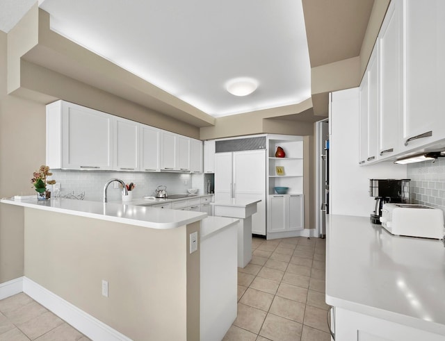 kitchen with white cabinetry, a peninsula, and light tile patterned floors