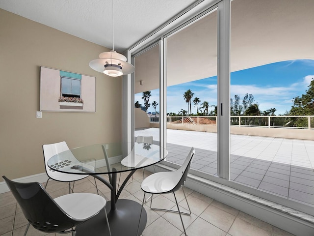 dining space with a textured ceiling, baseboards, and light tile patterned floors