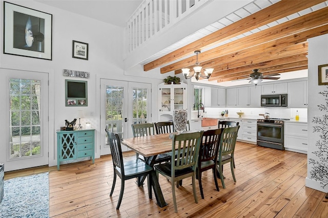 dining area featuring a healthy amount of sunlight, beamed ceiling, ceiling fan with notable chandelier, and light hardwood / wood-style floors