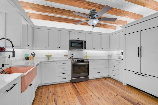 kitchen with white cabinets, range, sink, light wood-type flooring, and beam ceiling