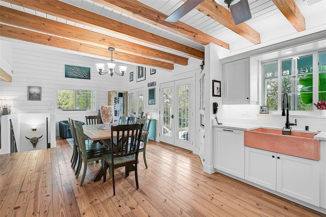 dining area featuring light wood-type flooring, sink, french doors, and beamed ceiling