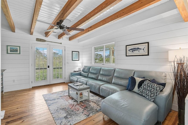 living room with light wood-type flooring, a healthy amount of sunlight, wood walls, and beamed ceiling