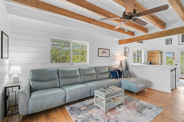 living room featuring a healthy amount of sunlight, beamed ceiling, and light hardwood / wood-style flooring