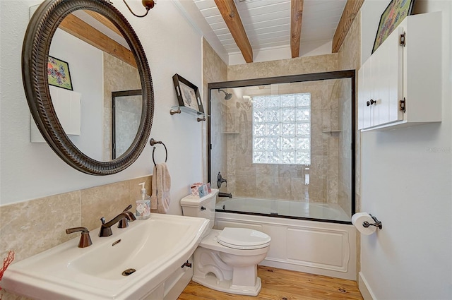 full bathroom featuring toilet, hardwood / wood-style flooring, bath / shower combo with glass door, beam ceiling, and sink