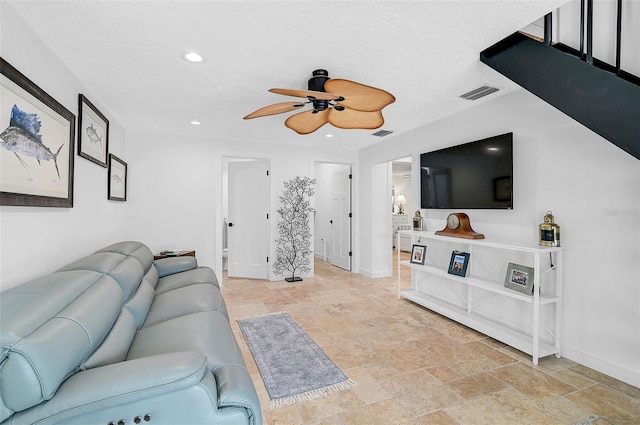 living room with ceiling fan and a textured ceiling